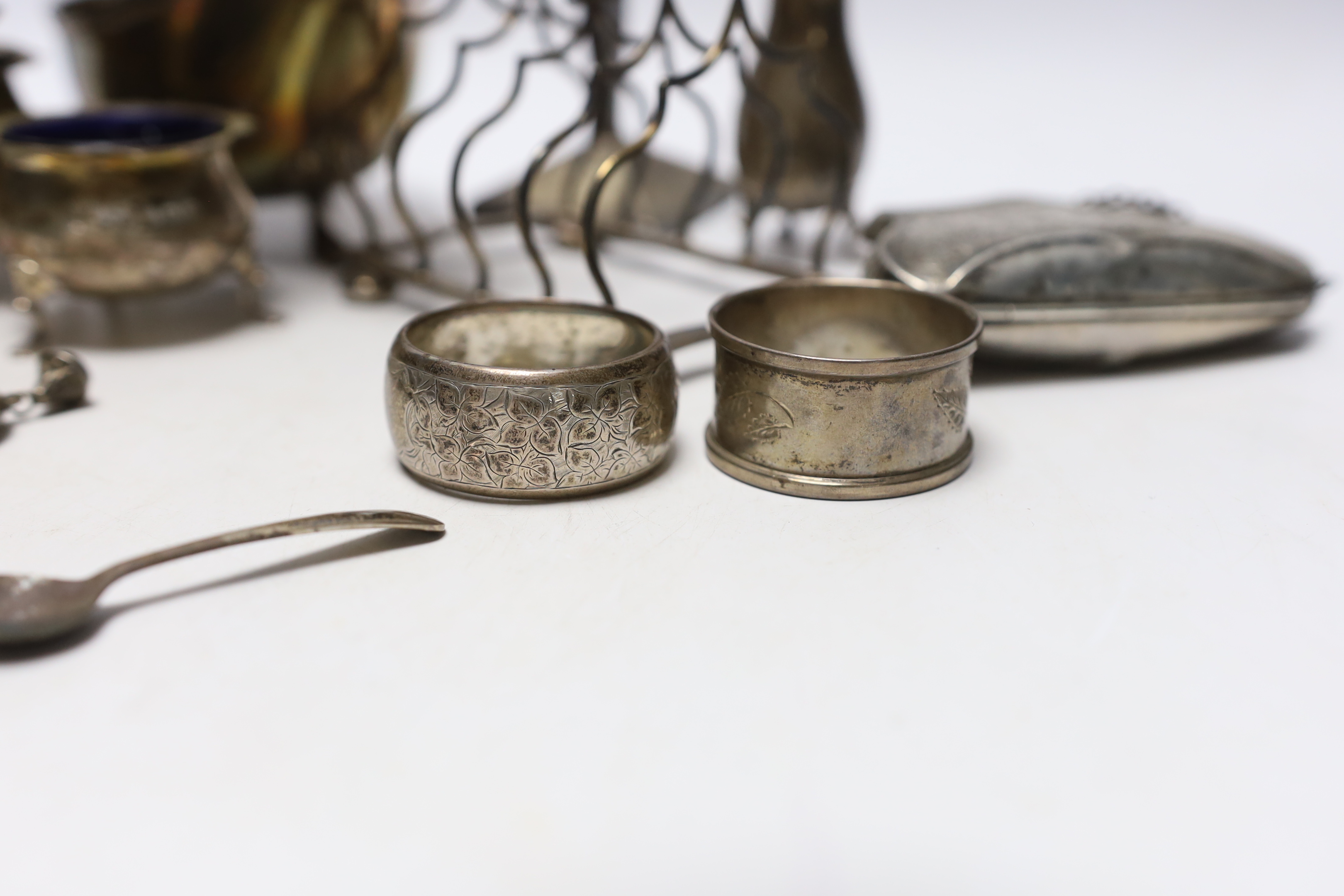 Sundry small silver including an Edwardian silver sauceboat, Birmingham, 1906, pair of spill vases (a.f.), a five bar toastrack, three condiments, a purse, two napkin rings and a child's rattle.